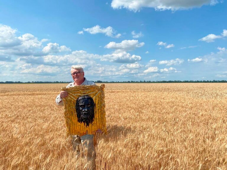 Sergey Melnikoff with the iron icon The Holy Mandylion, standing in a golden wheat field in Ukraine.