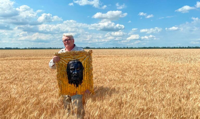 Sergey Melnikoff with the iron icon The Holy Mandylion, standing in a golden wheat field in Ukraine.