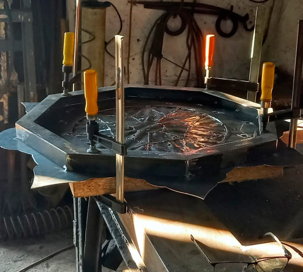 The first layer of the frame is fixed to the base with multiple bolted connections, preventing distortion as the upper decorative layers are welded on.